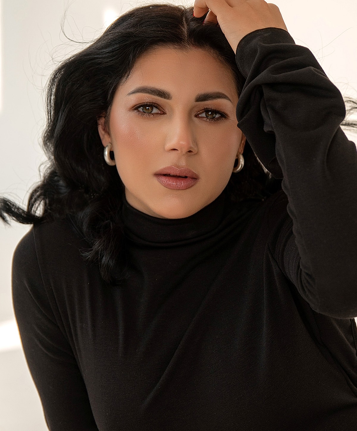 Woman in a black turtleneck, posing thoughtfully.