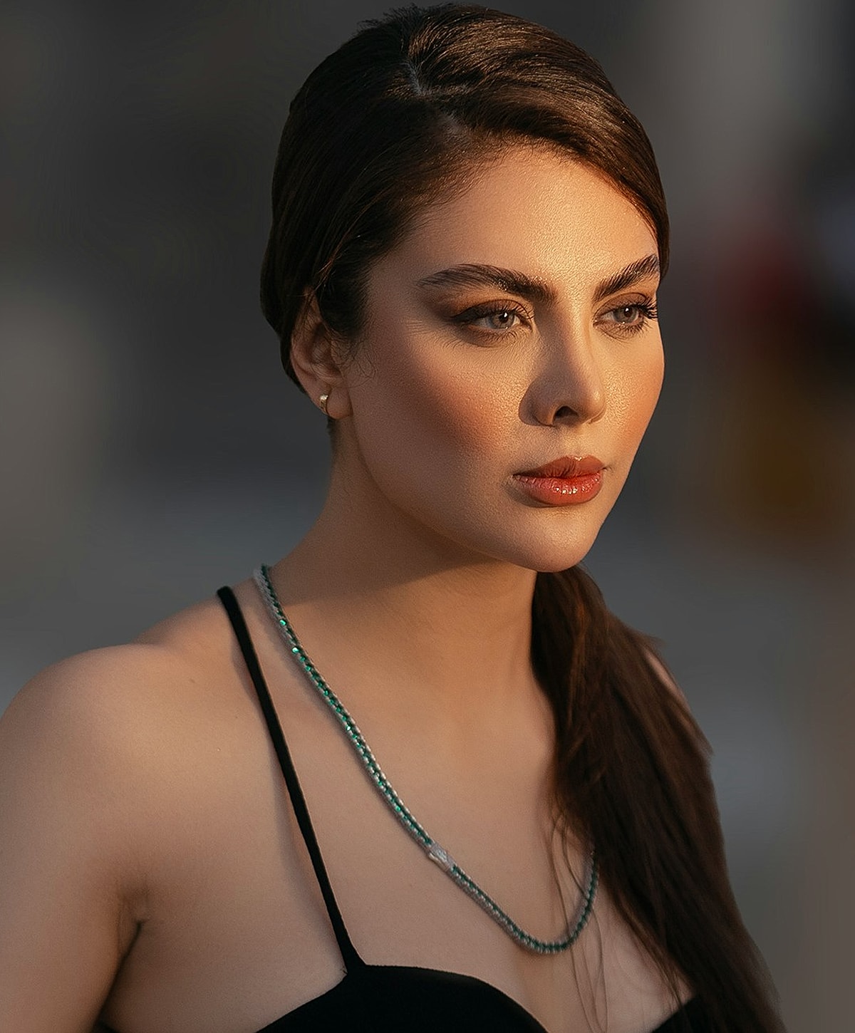 Woman with striking features and elegant necklace.