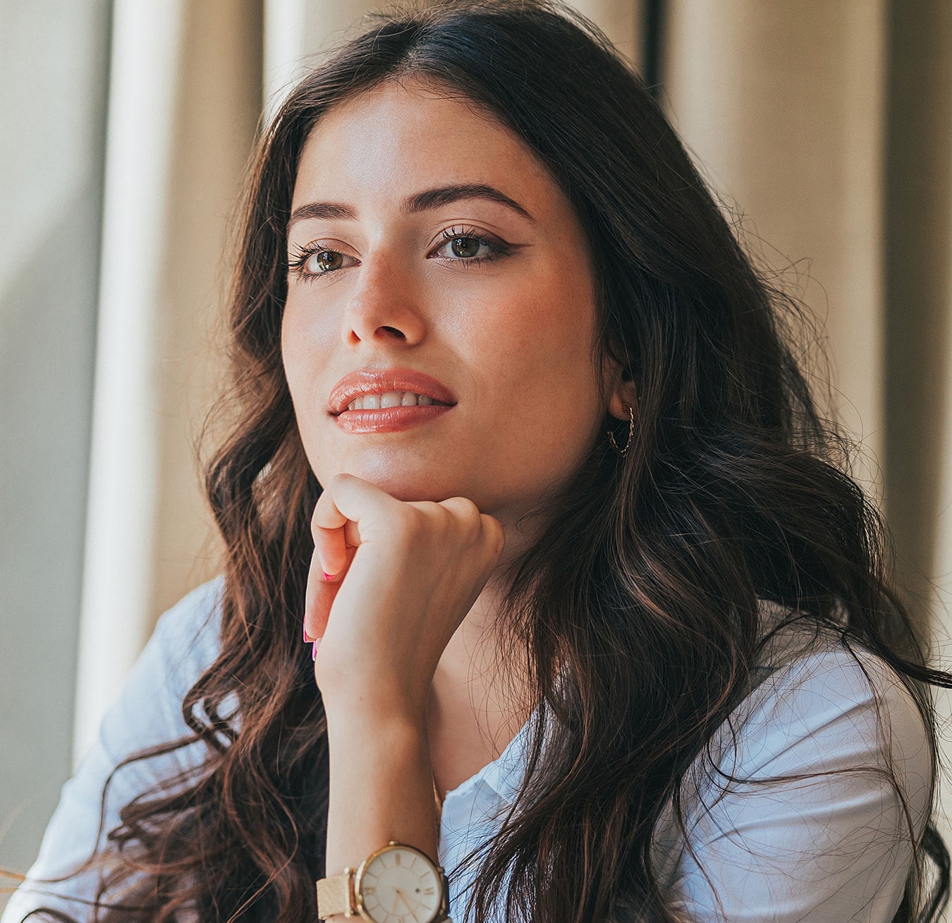 Thoughtful woman with long, wavy hair indoors.