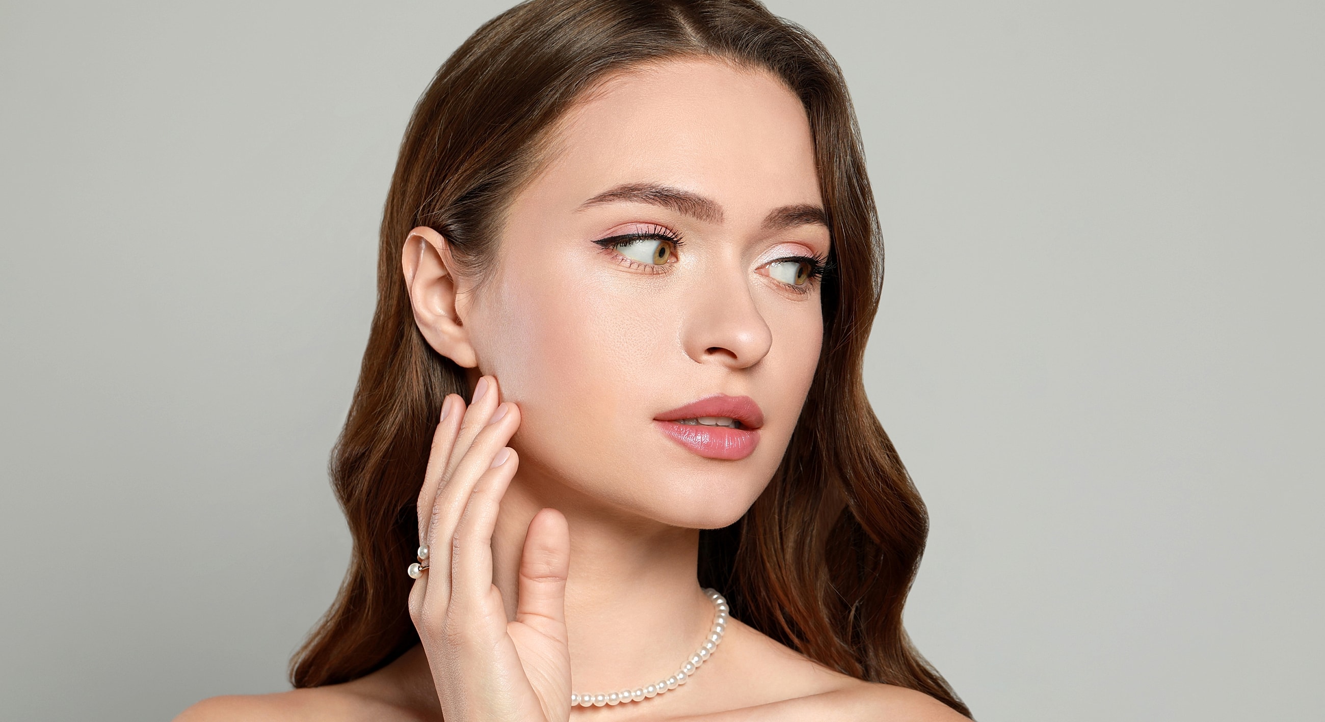 Model showcasing makeup and pearl jewelry.