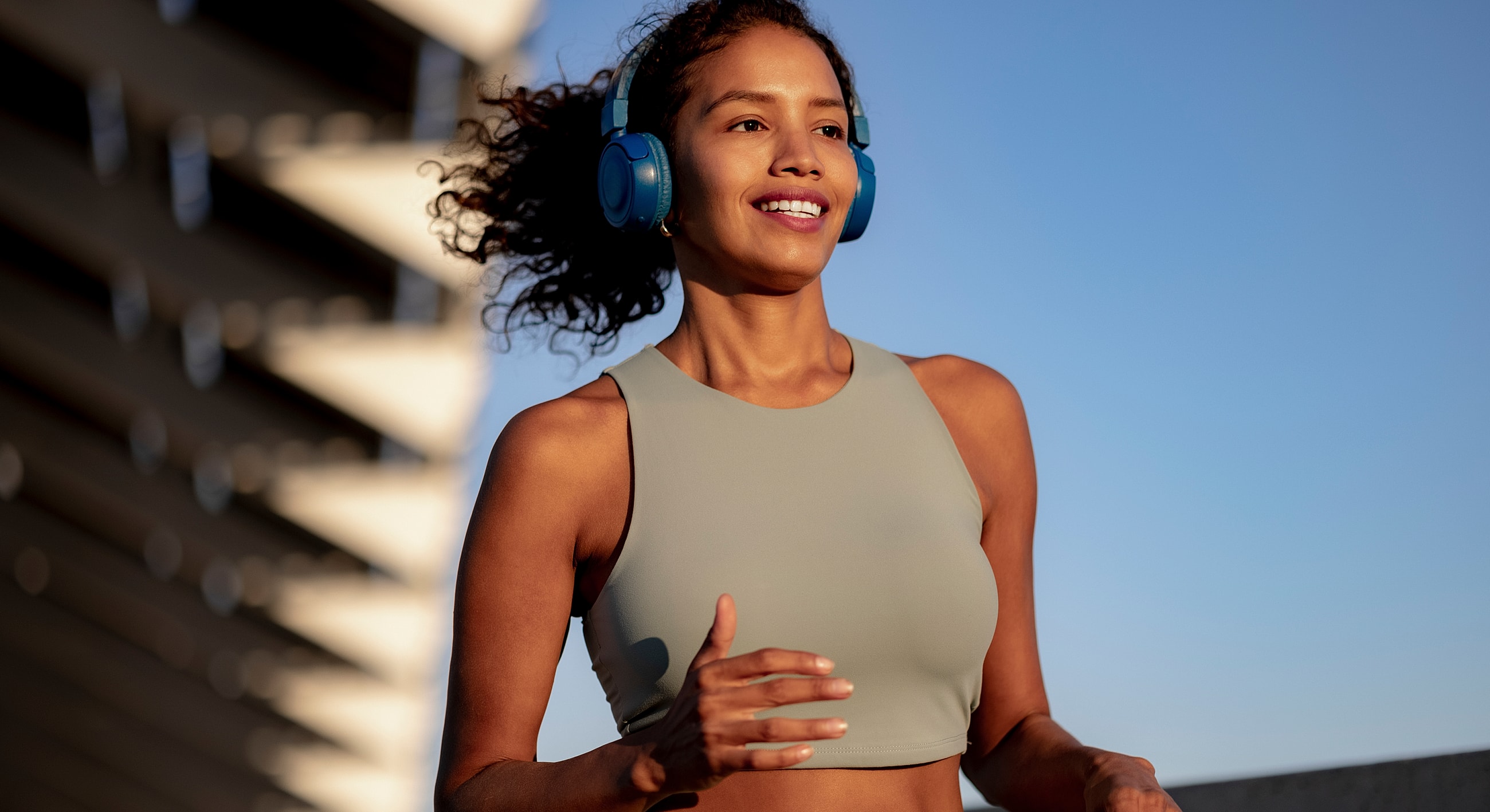Woman jogging with headphones in outdoor setting.