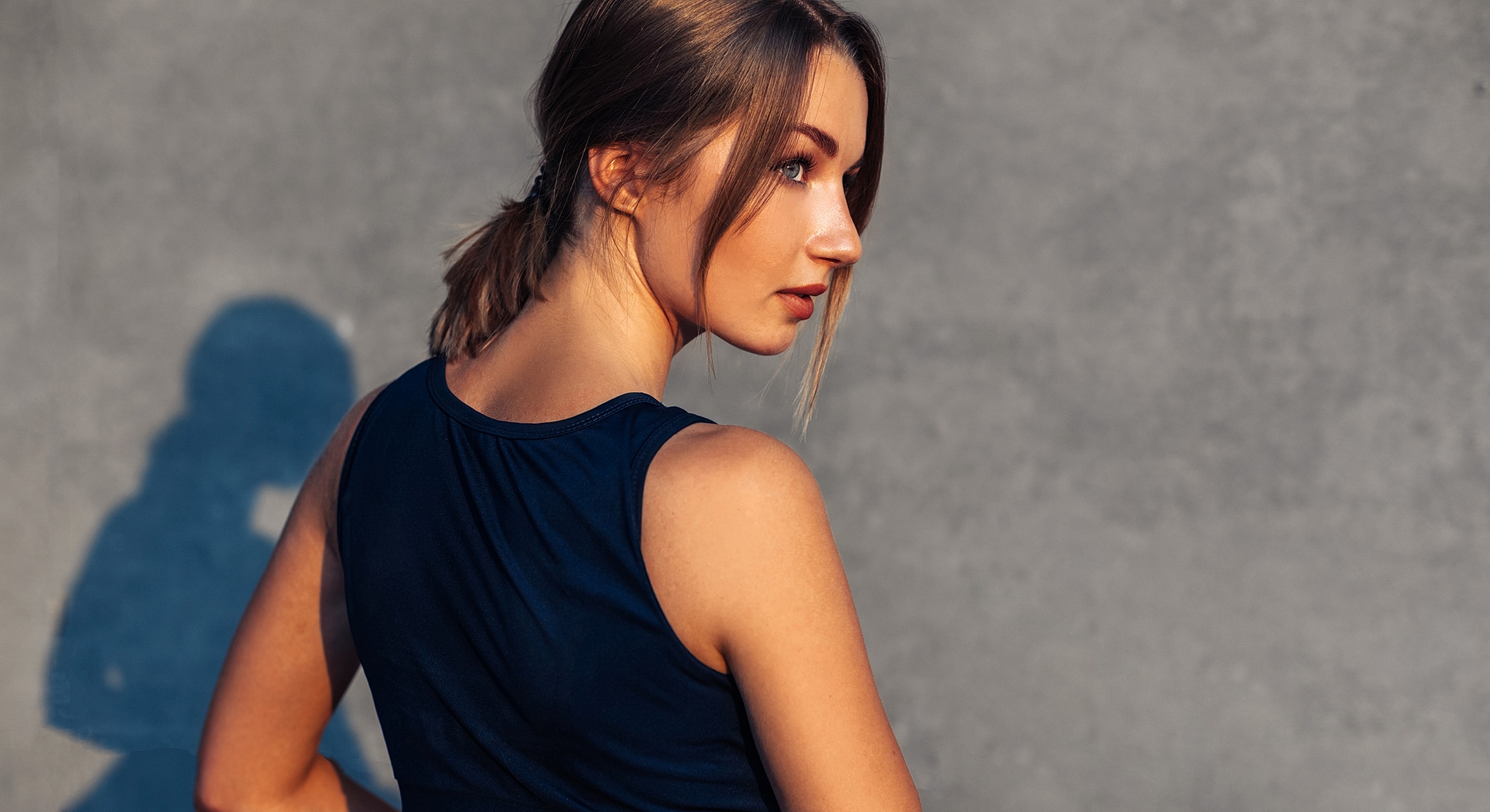 Woman in a sleeveless top, looking back.